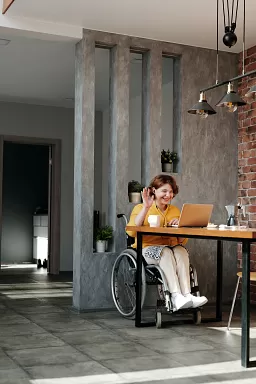 A person in a wheelchair working from home at their dining table.
